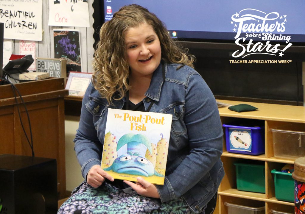 Elementary music teacher singing and reading a book in school