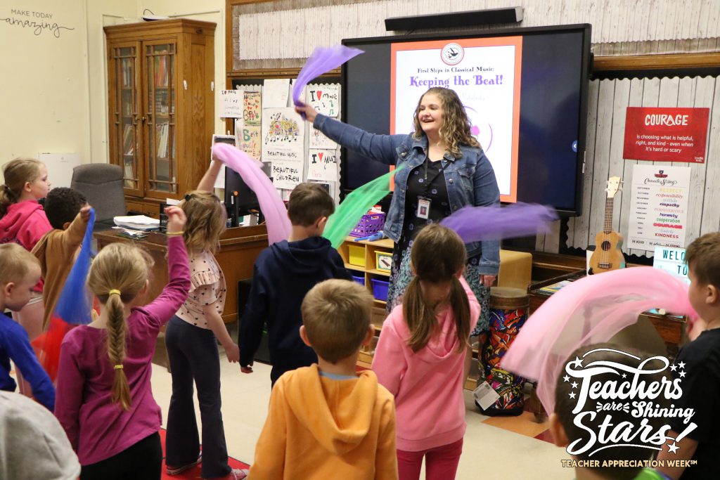 enthusiastic music teacher leads elementary students in waving colorful scarves to the beat of a tune