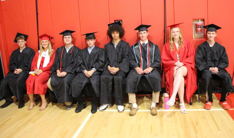 group of graduates in red and black caps and gowns before the commencement ceremony