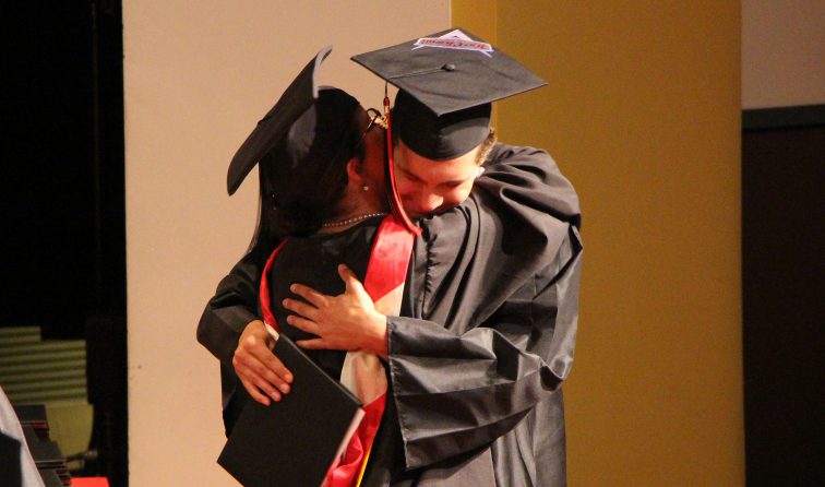 A graduate hugs and gets his diploma from his mom, a staff member of GFSD