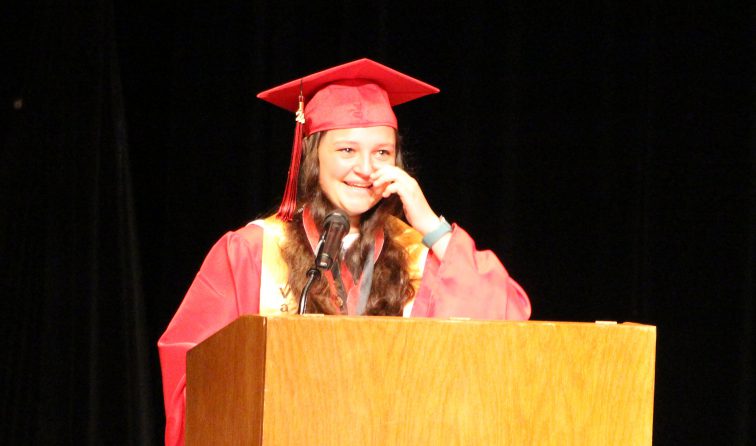Valedictorian wipes away a tear while smiling and giving her speech at commencement