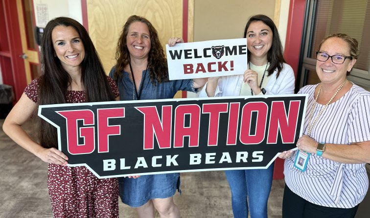 four school staff members smiling and holding a GF Nation Black Bears sign