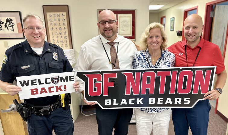 the principal, assistant principals and SRO smiling and holding a GF Nation Black Bears sign