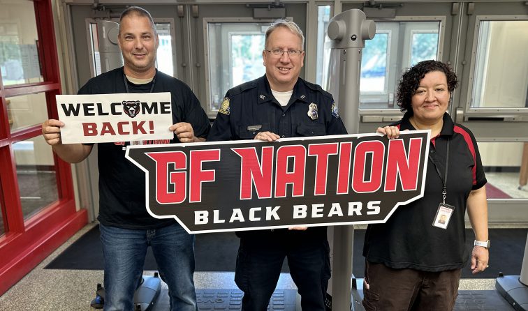 three school staff members smiling and holding a GF Nation Black Bears sign