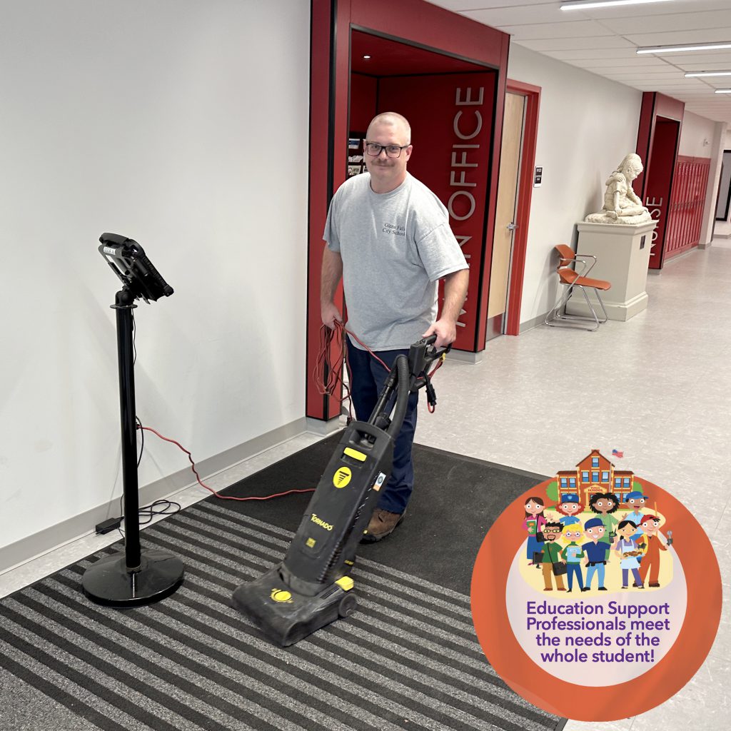 Custodian vacuuming the rug near the main entrance of GFMS